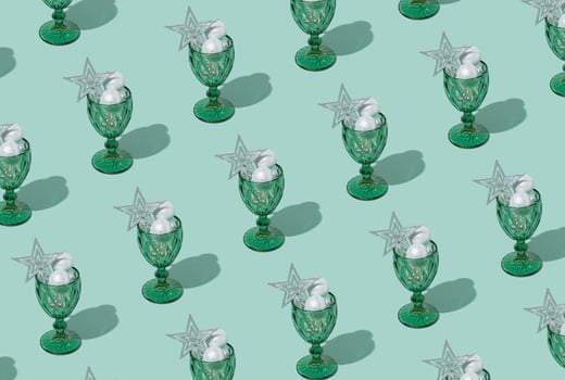 Pattern made of Christmas baubles cocktail decoration in wine glass on pastel green background. New year or Christmas eve party concept. photo