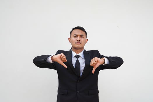 Portrait Young handsome Asian businessman dislike gesture with thumb down isolated on white background photo