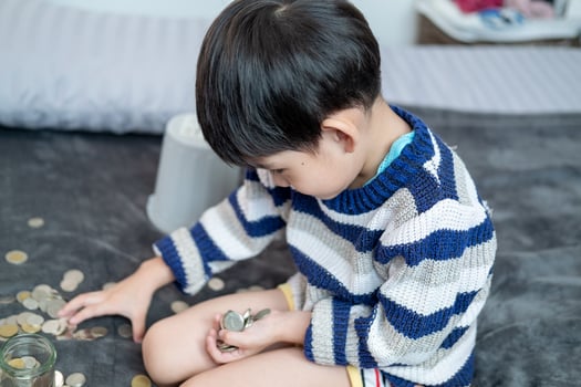 Asian boy happily counting coins to save money photo