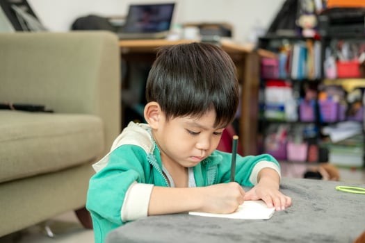 A boy is drawing pictures on a notebook on the table. Learning outside the classroom photo