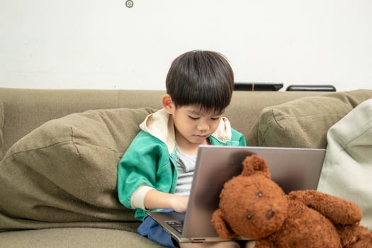 Asian boy studying online and doing activities on laptop photo