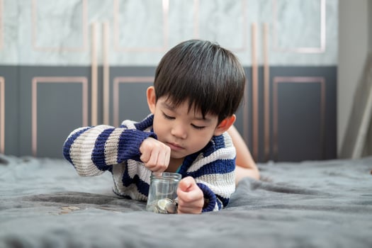 Asian boy happily counting coins to save money photo
