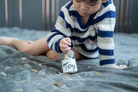 Asian boy sits and puts coins in a glass jar to save money to buy toys. photo