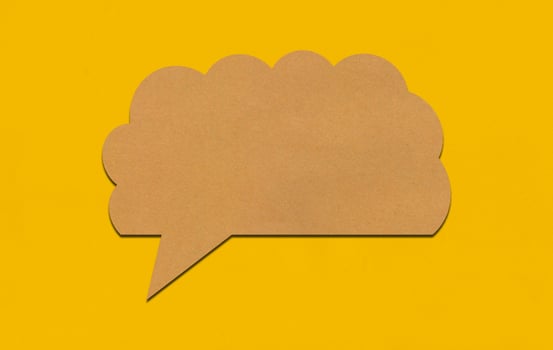 Brown paper speech bubble on yellow paper background. photo