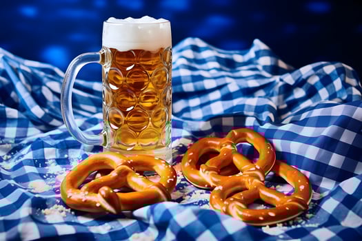 Oktoberfest beer mugs and pretzels on a wooden table with traditional towel at blue background. photo