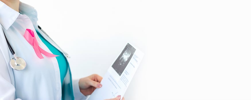 Woman doctor with pink ribbon on white medical uniform holds results of ultrasound scan in her hands. Breast cancer awareness month symbol. photo