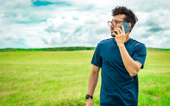 Handsome man calling on the phone in the field. man on the road talking on the phone, person in the field calling on the phone, young man talking on the phone in the field looking to the side photo