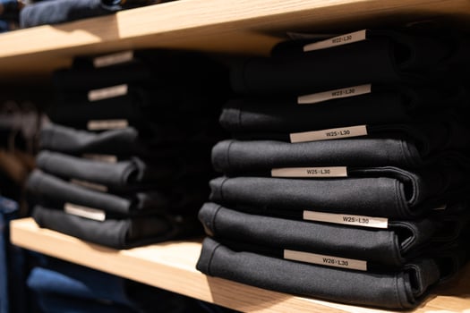Stacks of folded jeans on the shop shelves in the showroom or store. Clothes storage. Fashion retail shop inside shopping mall. photo