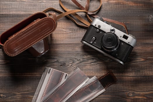 Vintage film camera with leather case and photographic film on dark wooden table. The view from the top photo
