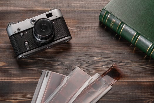 Vintage film camera, film and photo album on a dark wooden table. Top view