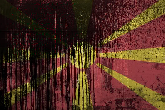 Macedonia flag depicted in paint colors on old and dirty oil barrel wall closeup. Textured banner on rough background photo