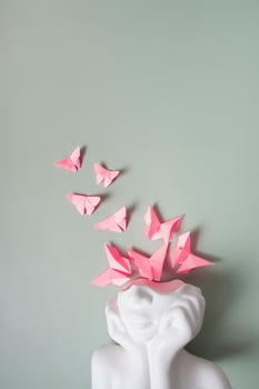 Mental health, mind care concept. A figurine of a head with butterflies on a colored background photo