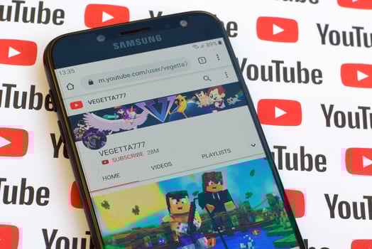 Vegetta777 official youtube channel on smartphone screen on paper youtube background. photo