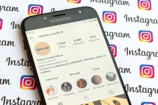 Roberto Cavalli official instagram account on smartphone screen on paper instagram banner. photo