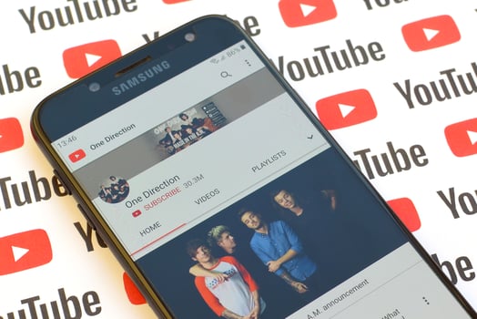 One Direction official youtube channel on smartphone screen on paper youtube background. photo