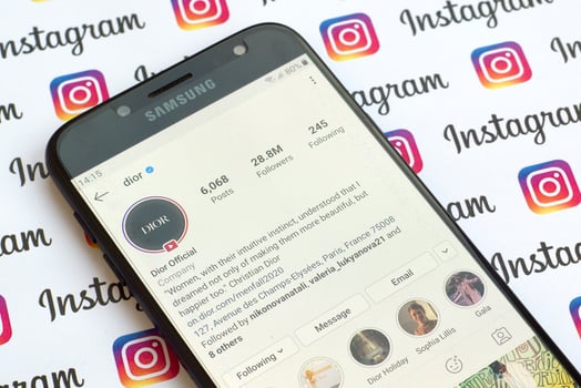 Dior official instagram account on smartphone screen on paper instagram banner. photo