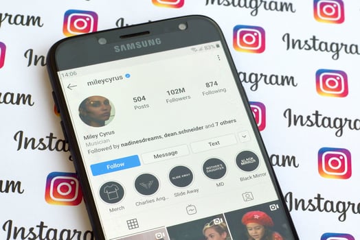Miley Cyrus official instagram account on smartphone screen on paper instagram banner. photo