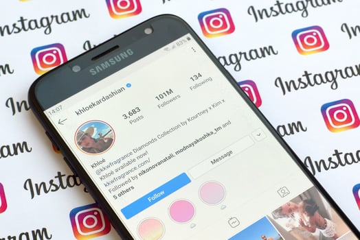 Khloe Kardashian official instagram account on smartphone screen on paper instagram banner. photo