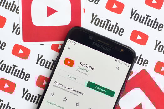 Youtube app on samsung smartphone screen on paper banner with small youtube logos and inscriptions. YouTube is Google subsidiary and American most popular video-sharing platform photo