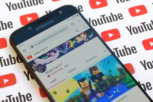 Vegetta777 official youtube channel on smartphone screen on paper youtube background. photo