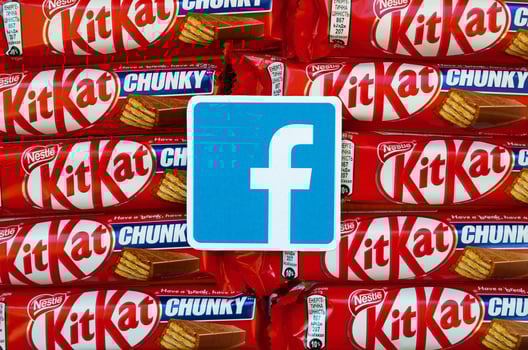 Facebook paper logo on many Kit Kat chocolate covered wafer bars in red wrapping. Advertising chocolate product in Facebook social network and world wide web photo