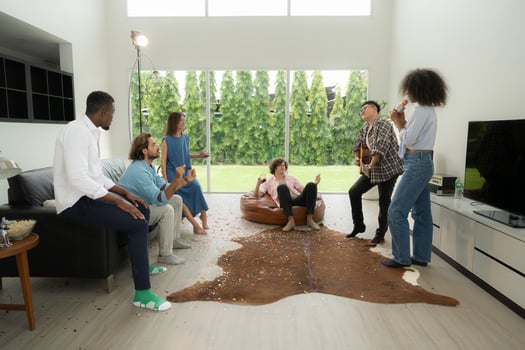 Group of multiethnic friends having fun at party by playing guitar and singing together at home. photo