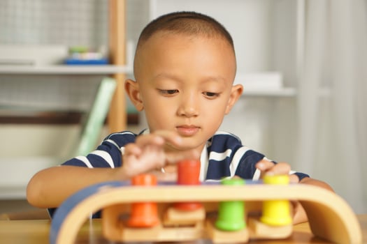 A boy plays with developmental toys on the table inside the house. photo