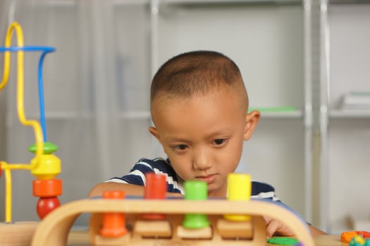 A boy plays with developmental toys on the table inside the house. photo
