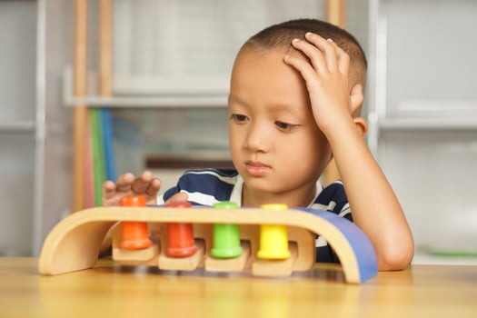 A boy plays with developmental toys on the table inside the house. photo