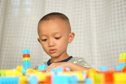 Asian boy playing with educational toys There are many beautiful colors on the table in the house. photo