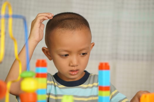 Asian boy playing with educational toys There are many beautiful colors on the table in the house. photo