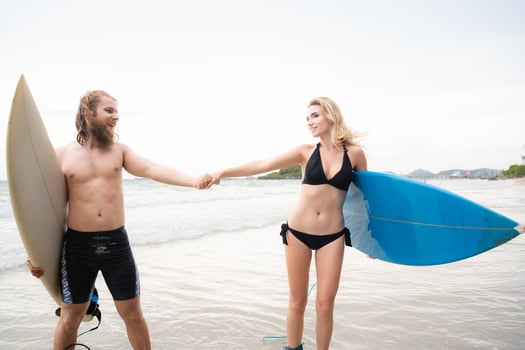 Couple of surfers holding hands and looking at each other on beach photo