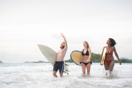 Two women and young man holding surfboards ready to walk into the sea to surf. photo