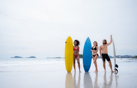 Group of friends in swimsuits posing with surfboards on the beach. photo