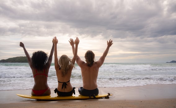 Rear view of three friends sitting on surfboard and looking at sea photo