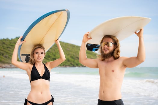 Young man and woman holding surfboards on their heads and walk into the sea to surf photo