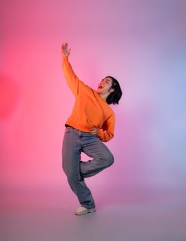 Image of a young Asian person dancing on a neon colored background photo