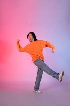 Image of a young Asian person dancing on a neon colored background photo