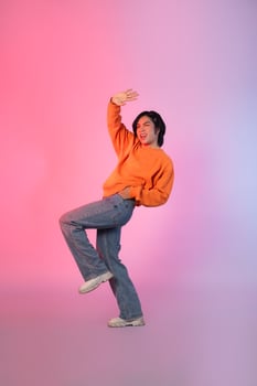 Image of a young Asian person dancing on a neon colored background photo