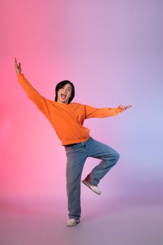 Image of a young Asian person dancing on a neon colored background photo