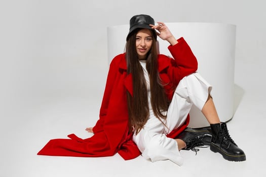 Fashionable  model in stylish  hat, red coat and boots  posing on white background in studio. photo