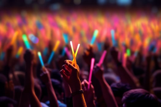 A close-up shot of hands holding glow sticks in the air at a rave party with a blurry crowd of people dancing in the background. Generative Ai photo