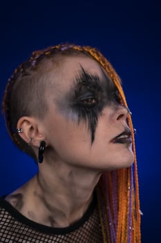 Dramatic portrait of informal woman with horror stage makeup on face, colored dreadlocks hairstyle photo