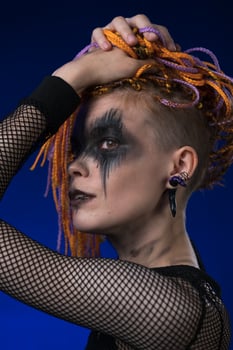 Headshot of young woman with horror black stage make up painted on face, color dreadlocks hairstyle photo
