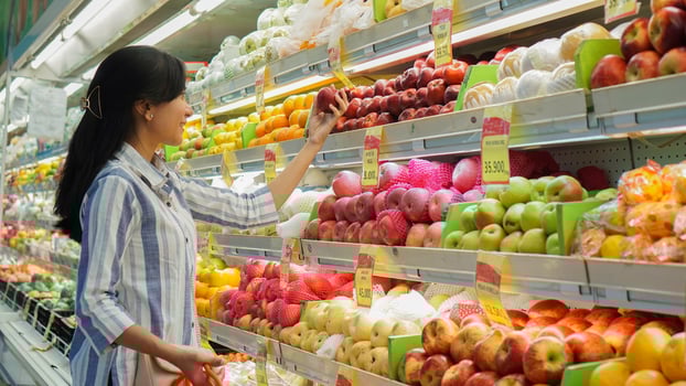 portrait of a beautiful Asian or Indonesian woman buying fruit arranged on fruit rack in a supermarket photo