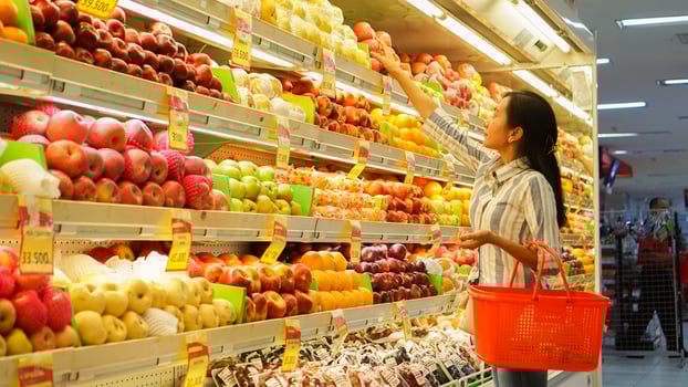 portrait of a beautiful Asian or Indonesian woman buying fruit arranged on fruit rack in a supermarket photo