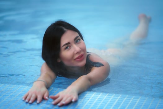 Adult brunette relaxation lies in geothermal water in pool at spa resort photo