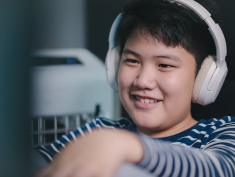 Lifestyle Asian little boys smile use desktop PCs computer to play professional video games with headphones in the house, Chat with friends, and Entertainment photo