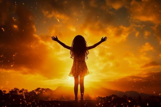Preteen girl silhouette with raised hand over sunset sky embracing nature photo