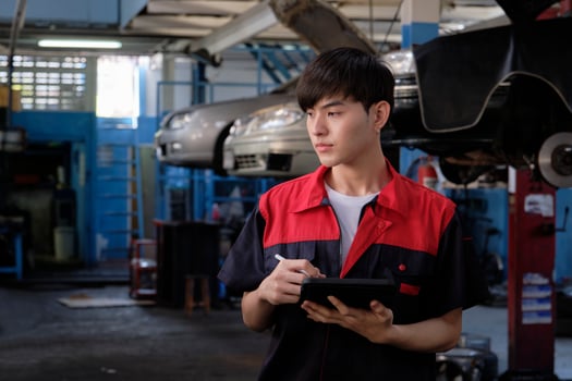 One male Asian professional mechanic, supervisor engineer, inspects repair work checklists with tablet at garage, service car maintenance, and fixing specialist occupations in auto transport industry. photo